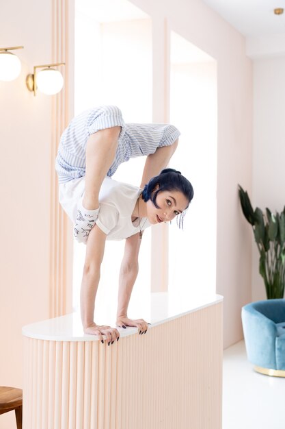 Flexibel meisje oefent zich uit en handstand thuis concept van individualiteit, creativiteit en zelf ...