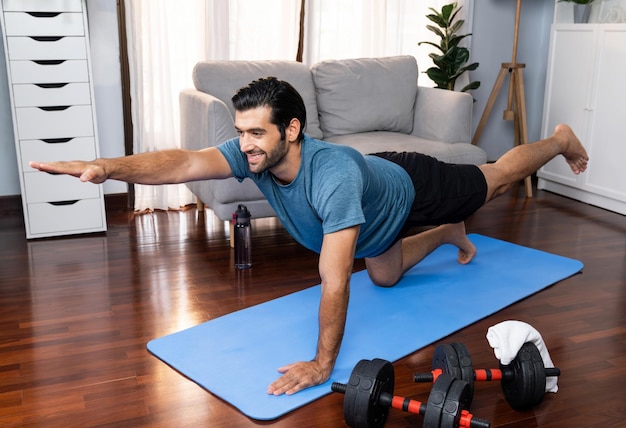 Flexibele en behendige man in sportkleding die omgekeerde vrolijkheid yoga-positie doet