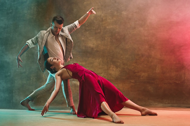 Flexibele jonge moderne paar tango dansen in studio. Mode portret van aantrekkelijk dansend paar. Man en vrouw. Passie. Dol zijn op. perfecte huid gezichts- en make-up. Menselijke emoties - liefde en passie