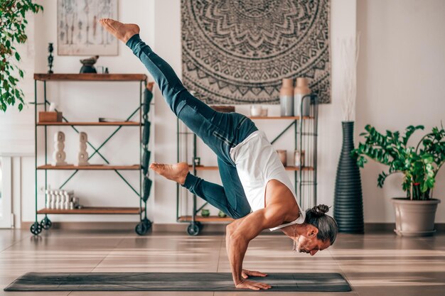 Foto flexibele man die thuis de flying crow-asana uitvoert