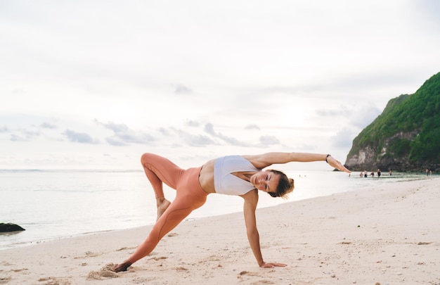 Flexibele vrouw die yoga op strand doet