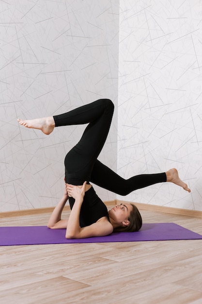 flexibele vrouw doet yoga in Supported Shoulder Stand pose terwijl ze ondersteboven balanceert op de mat