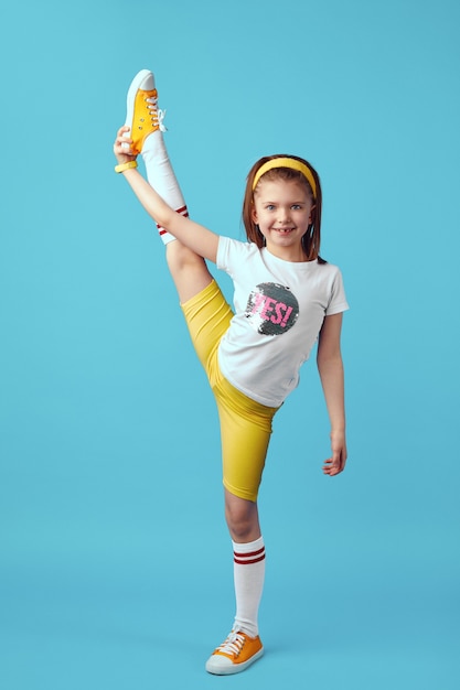 Flexible adorable child girl in yellow sportswear perform transverse twine