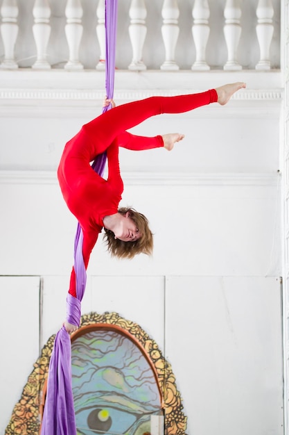 Flexible attractive woman air gymnast performs an exercise on aerial silk