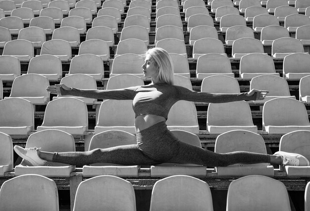 Flexible female athlete stretching on stadium outdoor in split sport