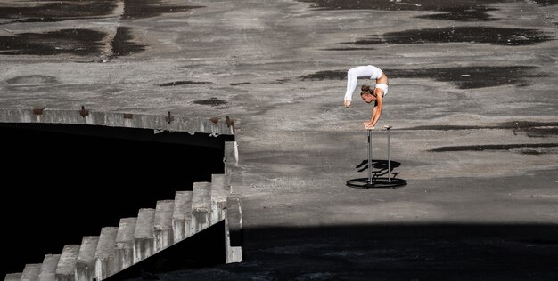 Flexible and fit girl standing on her hands keeping balance in the abandoned building. Concept of effort, self-development and healthy lifestyle.