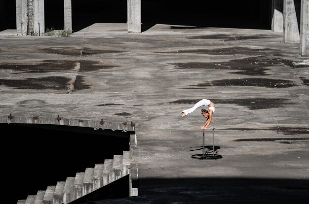 flexible and fit girl standing on her hands keeping balance in the abandoned building