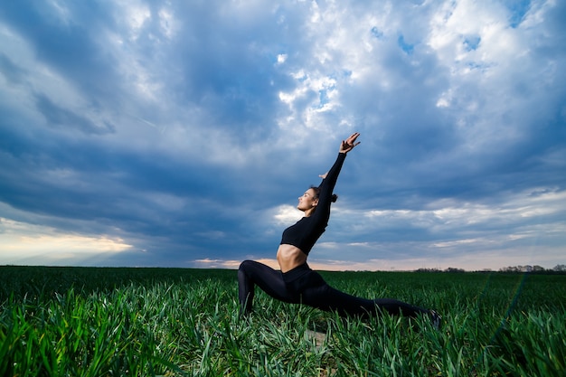 Photo flexible girl, acrobat, gymnastic bridge, handstand, graceful woman. in nature, performs beautiful poses for flexibility, a sports model on a blue sky background.