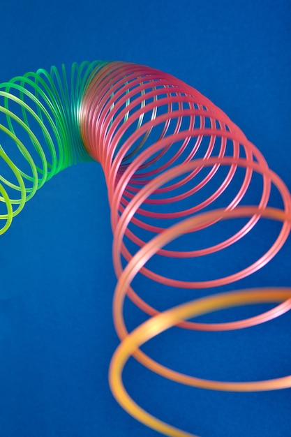 Photo flexible stretching multicolored slinky toy close up view with blurred foreground, place for text.