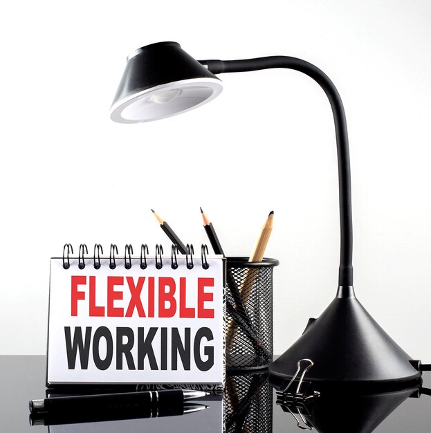 Foto flexible working tekst op notitieboekje met pen en tafellamp op de zwarte achtergrond