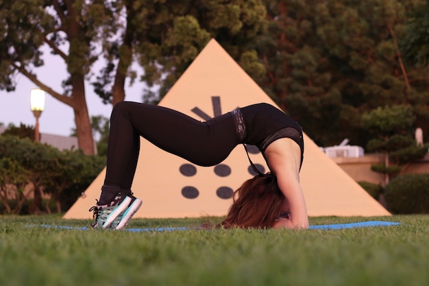 Foto la ragazza flessibile sull'erba fa una posa del ponte la flessibilità mette in mostra la salute dello yoga