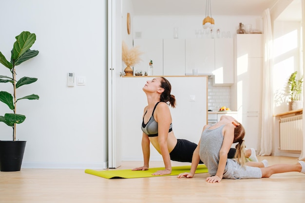 Flexible young mom and her son doing yoga together upward facing dog