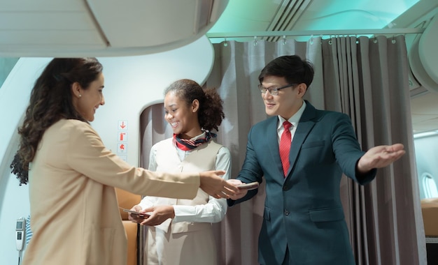 Flight attendant greet passengers as they enter the aircraft to locate a seat in the cabin