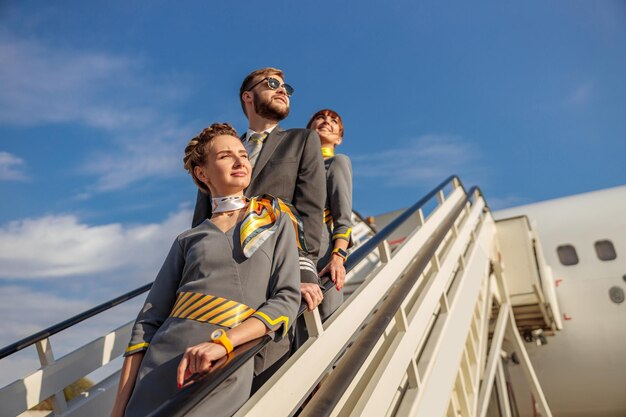 Flight attendants and pilot standing on airplane stairs