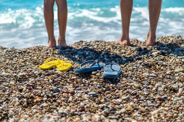 海のビーチでビーチサンダルと足。セレクティブフォーカス。