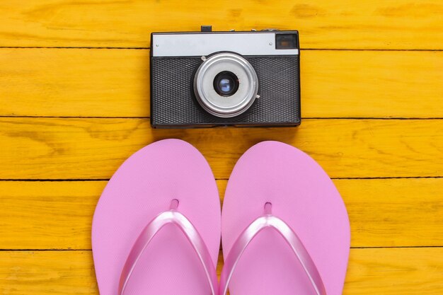 Flip flops met retro camera op een gele houten