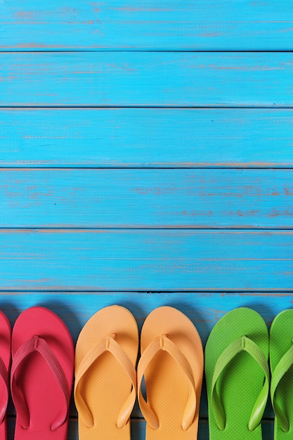 Photo flip flops in a row old weathered blue beach wood background vertical