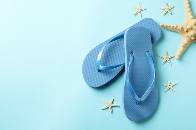 Flip flops and sea stars on blue background