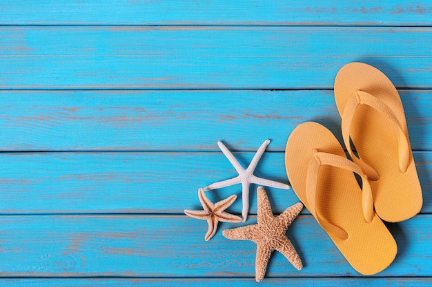 Photo flip flops starfish old distressed bright blue beach wood background