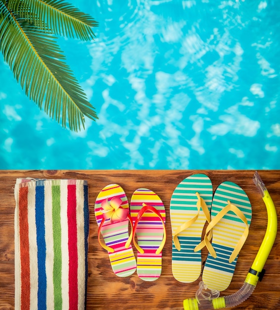 Flipflops op hout tegen blauw water Zomervakantie concept