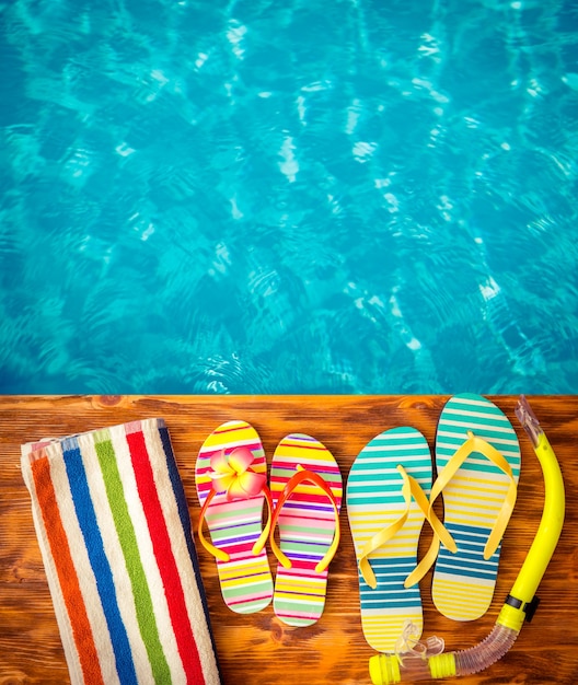 Flipflops op hout tegen blauw water Zomervakantie concept