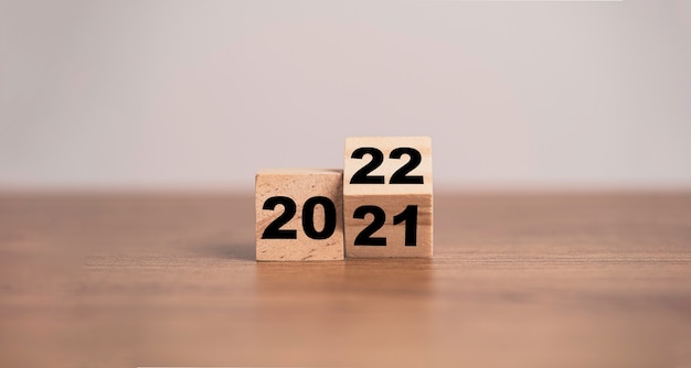 2021年から2022年に変更するための木製の立方体ブロックの反転。メリークリスマスと新年あけましておめでとうございますのコンセプト。