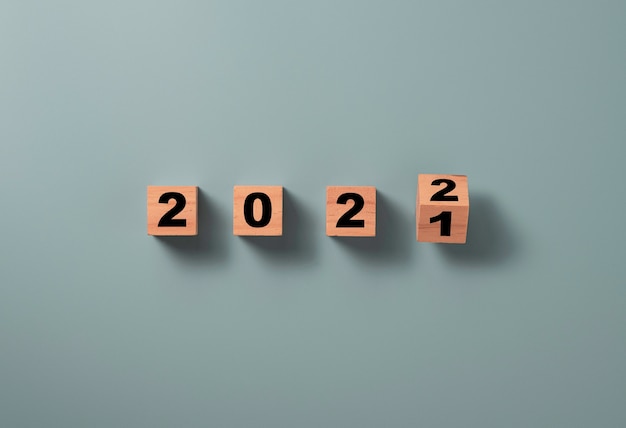 Flipping wooden block cube to change 2021 to 2022 on blue background, Merry Christmas and happy new year preparation concept.