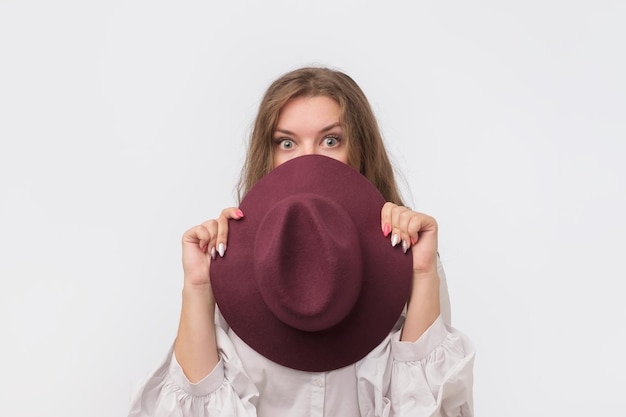 Photo flirty funky caucasian woman hiding behind fashionable trendy head wear with wide open eyes