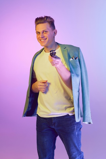 Flirty male look happiness young handsome smiling man in stylish jacket posing over purple