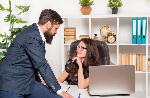 Flirty office manager flirting with director sitting on office desk work relation