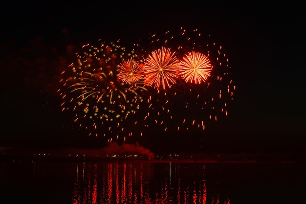 Flitsen van feestelijk vuurwerk boven de nachtrivier worden weerspiegeld in het water