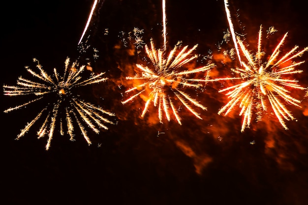 Flitsen van helder vurig rood en goud glinsterende vuurwerkkleuren tegen een zwarte nachtelijke hemel