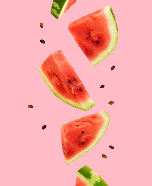 Floating, flying, levitating sliced fresh watermelon on pink background. Summer fruits, berries. Trendy, minimal Creative food. Concept of watermelon day-August 3.