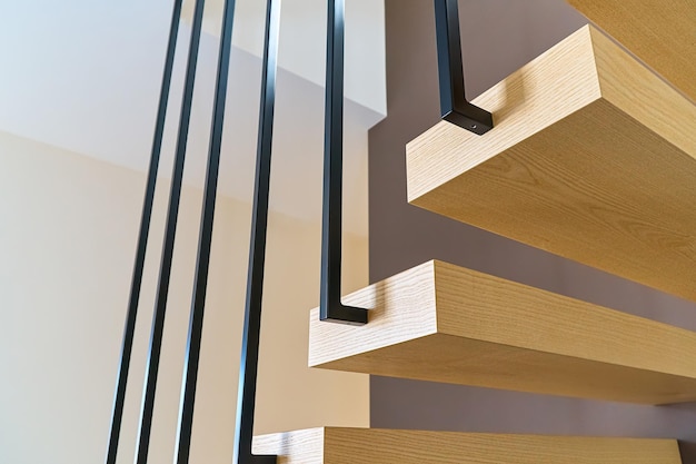 Floating stairs Ash lumber stairs with metal railing attached to brown wall and leading to second floor inside stylish modern house