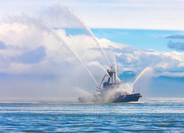 Floating tug boat is spraying jets of water