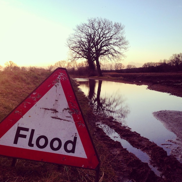 Flood sign by river during sunset