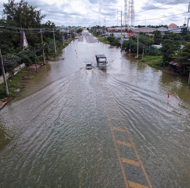 Flooded roads, people with cars running through. aerial drone\
photography shows streets flooding and people\'s cars passing by,\
splashing water.