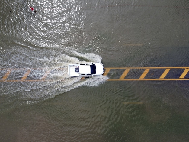 Flooded roads, people with cars running through. aerial drone\
photography shows streets flooding and people\'s cars passing by,\
splashing water.