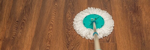 Photo floor care, wet cleaning at home. washing brown floor with a round mop. copy space