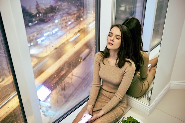 Floor to ceiling window with years old woman with closed eyes and handy in hands