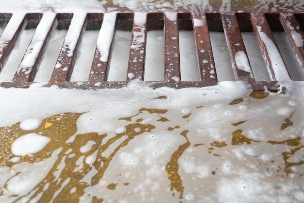 Floor grid with soap sud waste in car washing garage full frame
closeup with selective focus