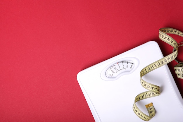 Floor scales and tape measure on a colored background top view