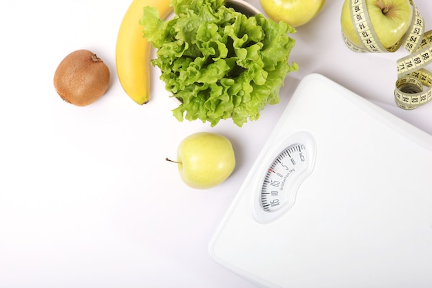 Floor scales tape measure and healthy products on a colored background top view