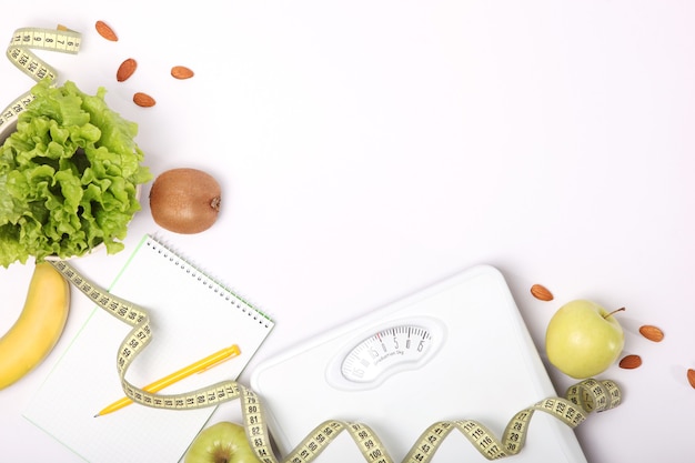 Floor scales tape measure and healthy products on a colored background top view