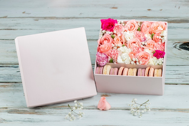 Composizione floreale di rose rosa con macarons di diversi colori