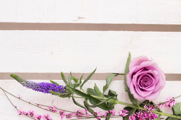 Floral arrangement with pink rose blossom on white wood