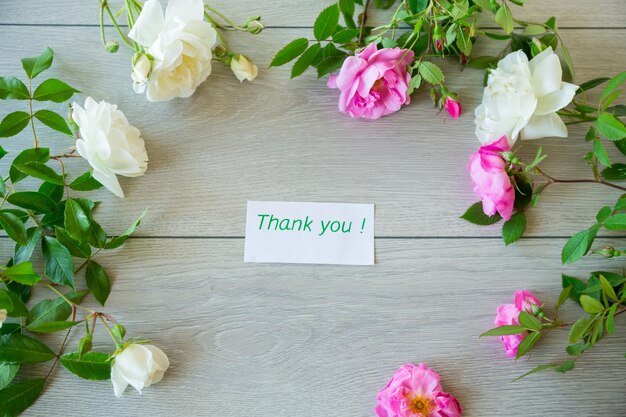 Floral background of pink and white roses on a light wooden table