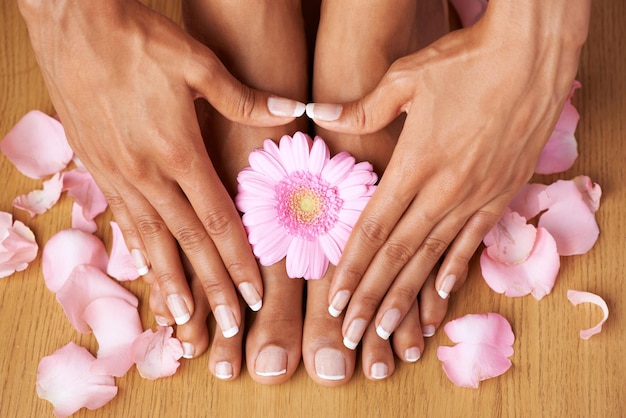 Floral beauty Cropped view of hands on perfectly pedicured feet with flowers all around