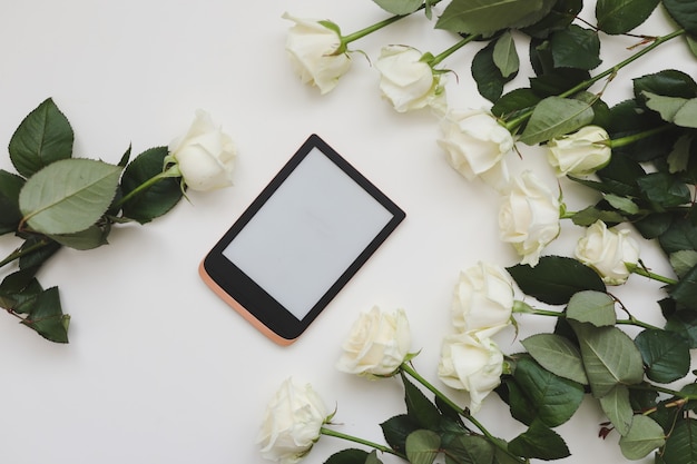 Floral composition with tablet fresh white roses on white table, flat lay, top view