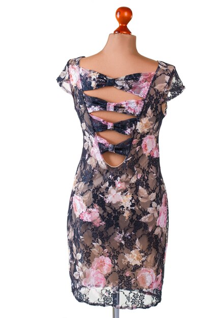 Floral dress with back cutouts. Dress on beige armless mannequin. Trendy garment with cutouts. Woman's attractive evening apparel.